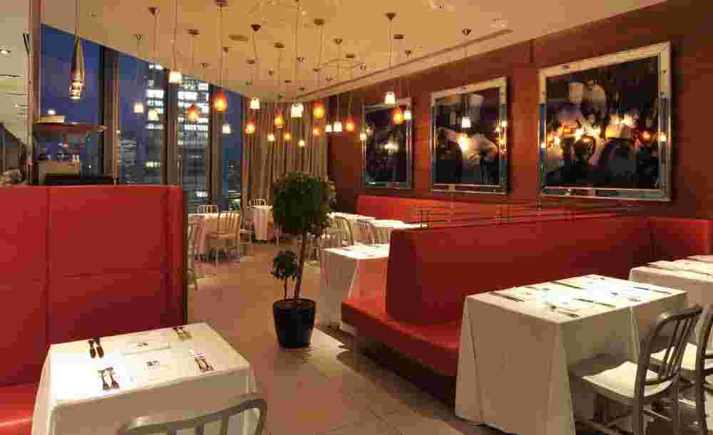 テーブル席と壁にシェフの写真。窓から夜景か見える店内。