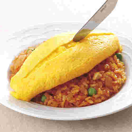 チキンライスの上のオムレツを切っている