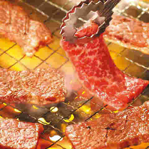 美味しそうな焼肉をトングで持ち上げている画像