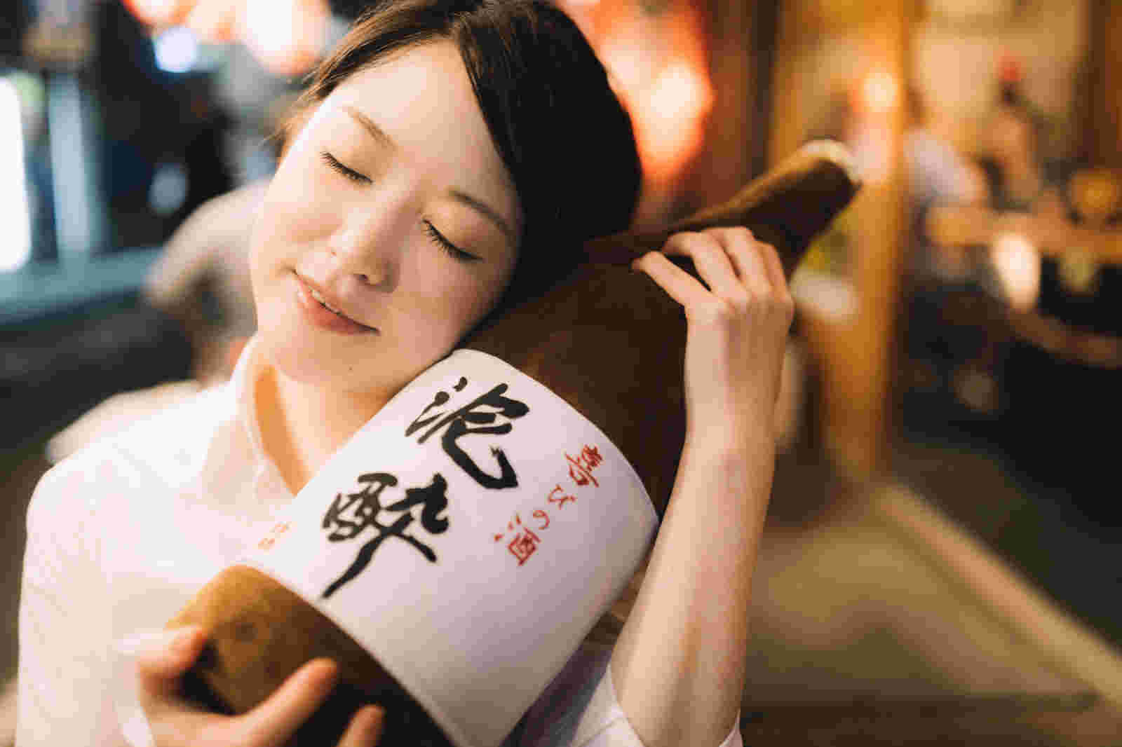 一升瓶のぬいぐるみを抱き満足そうな女性