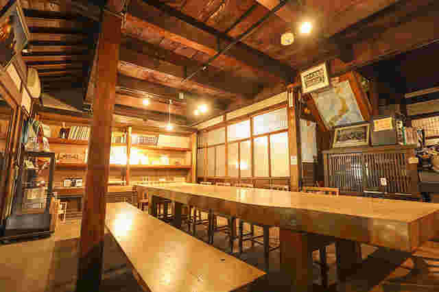 木の長いテーブルと長椅子、天井が見える店内