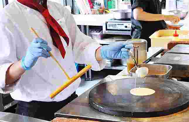 オープンキッチンで、クレープ生地を焼いているスタッフ
