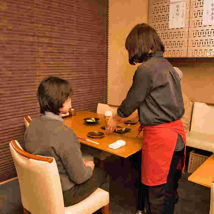 ランチする女性の前にビールを届ける店員