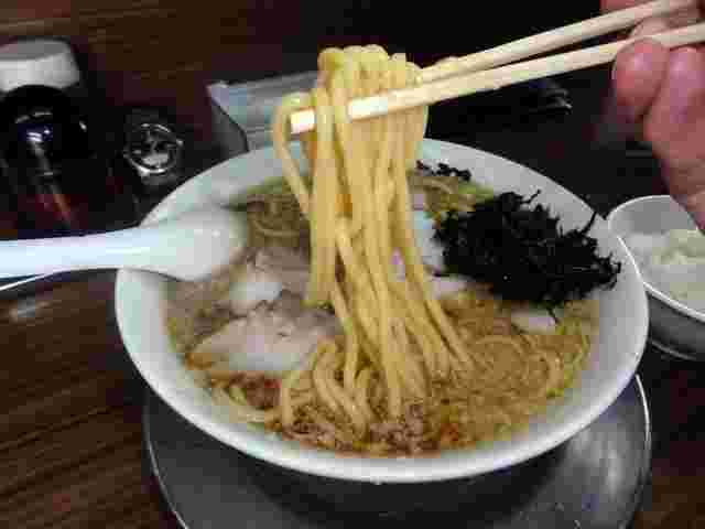 ラーメンを持ち上げている。
