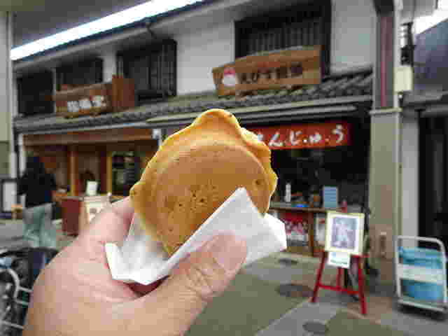 手に持った大判焼きと奥に店舗
