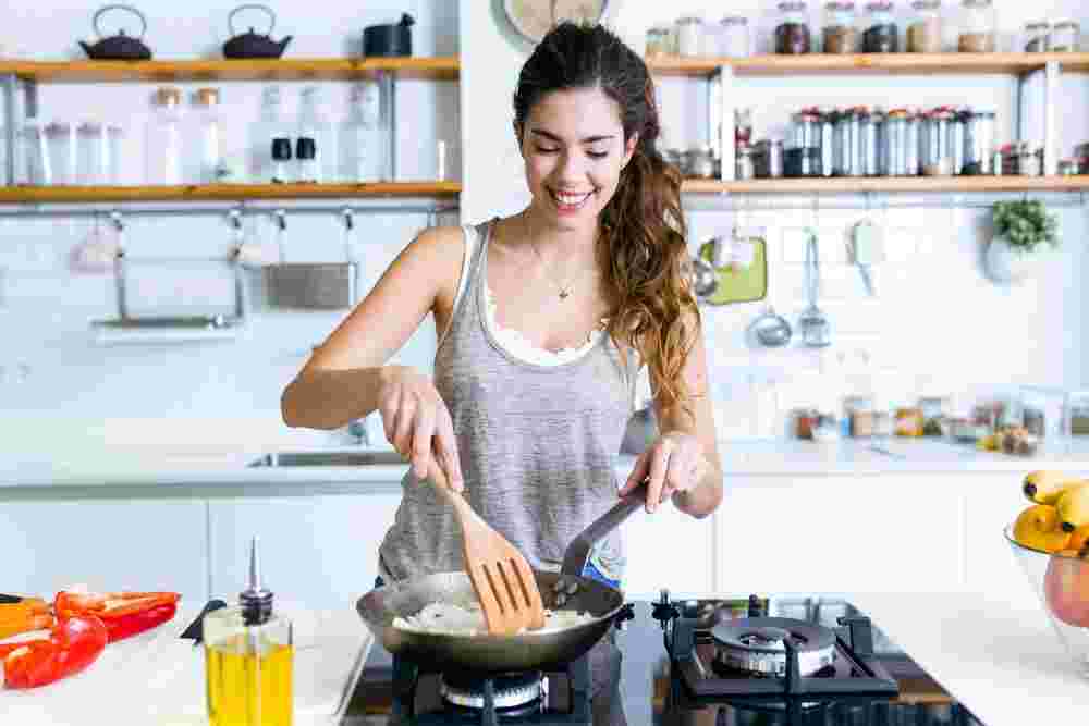 フライパンで食材を炒める女性