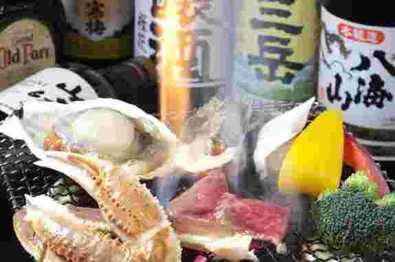 カニやホタテなどの魚介類やお肉と野菜が七輪で焼かれている画像
