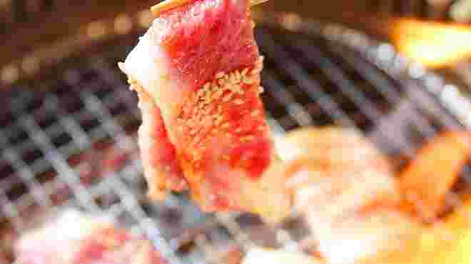 胡麻が沢山乗った牛肉を美味しそうに箸で持ち上げている画像