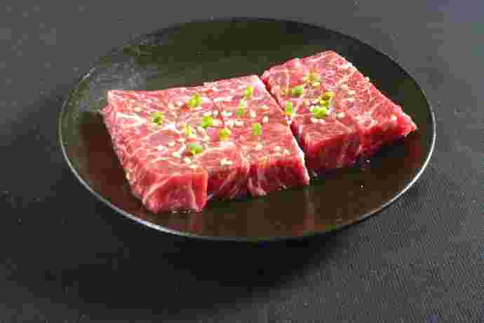 厚切りの牛ロースの上に小口ネギと胡麻が乗ったお肉の画像