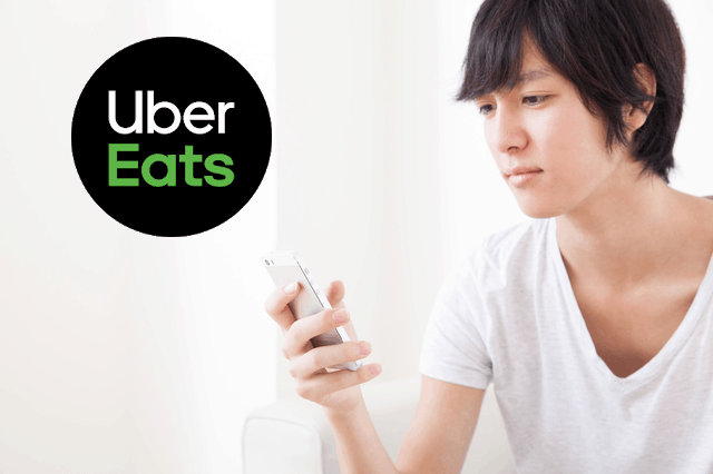 ウーバーイーツのロゴとアプリを操作する男性