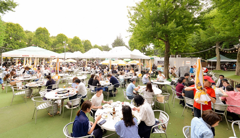 木々に囲まれ芝生の上でビアガーデンを堪能するお客たち