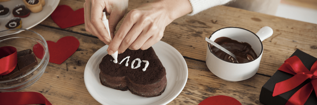 チョコレートケーキにチョコペンで文字を書いている