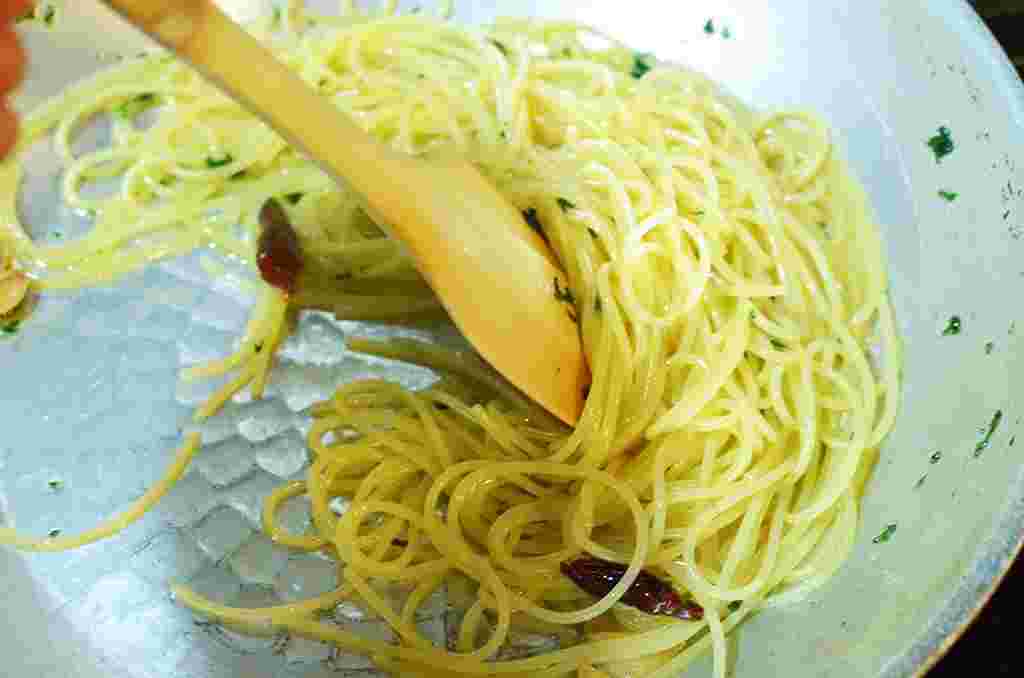 ペペロンチーノのソースにパスタを絡ませている様子