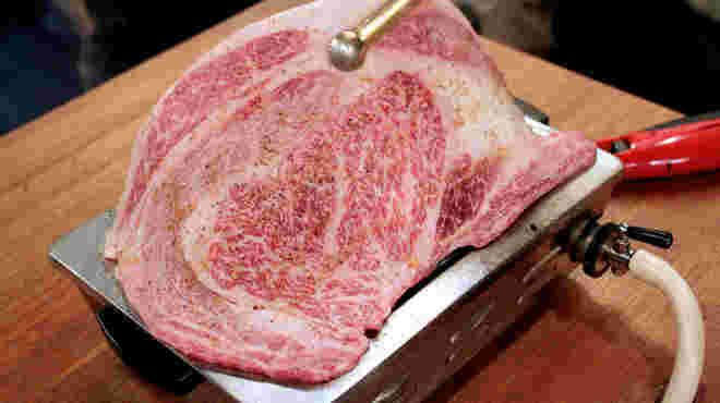 網に乗り切れないくらい大きな牛肉のステーキの画像