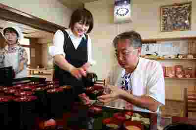 わんこそばを給仕にお椀へ注いでもらっているおじさん