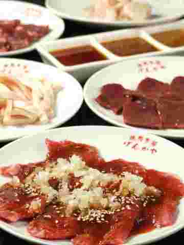 牛レバー、丸腸、刻みネギの乗ったタレの乗った牛肉の画像