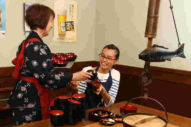 わんこそばを食べる客とそばを入れる給仕