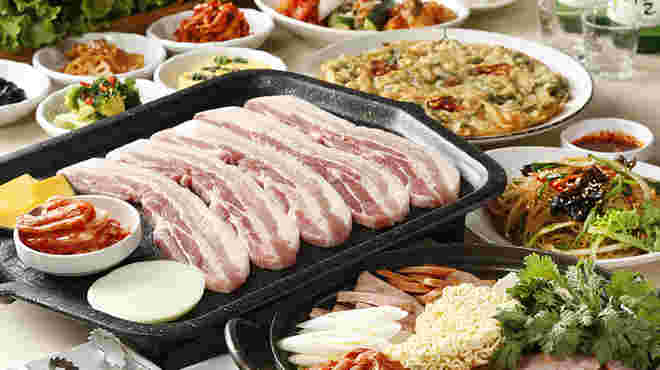テーブルの上に肉、野菜、チゲなど韓国料理が並んでいます