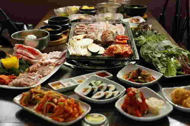 テーブルの上に焼肉、海苔巻きなどの韓国料理並んでいます