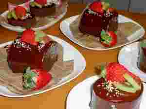 市販のロールケーキをチョコレートコーティングし、イチゴやキウイで飾りつけしたケーキ
