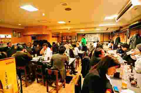 店内、テーブルに座って食事を楽しむ賑わう客