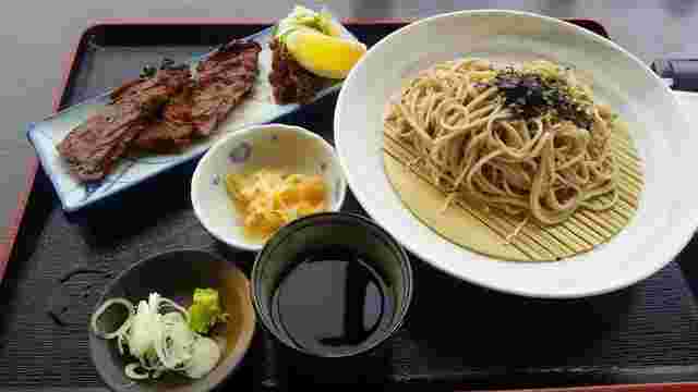 ざるそばや麺つゆ、薬味のネギ、ワサビなどが乗っているお膳の画像