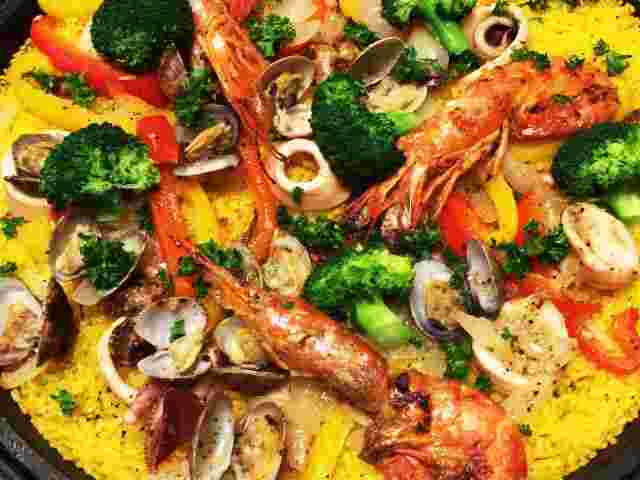 サフラン色のご飯の上に魚貝類とブロッコリー
