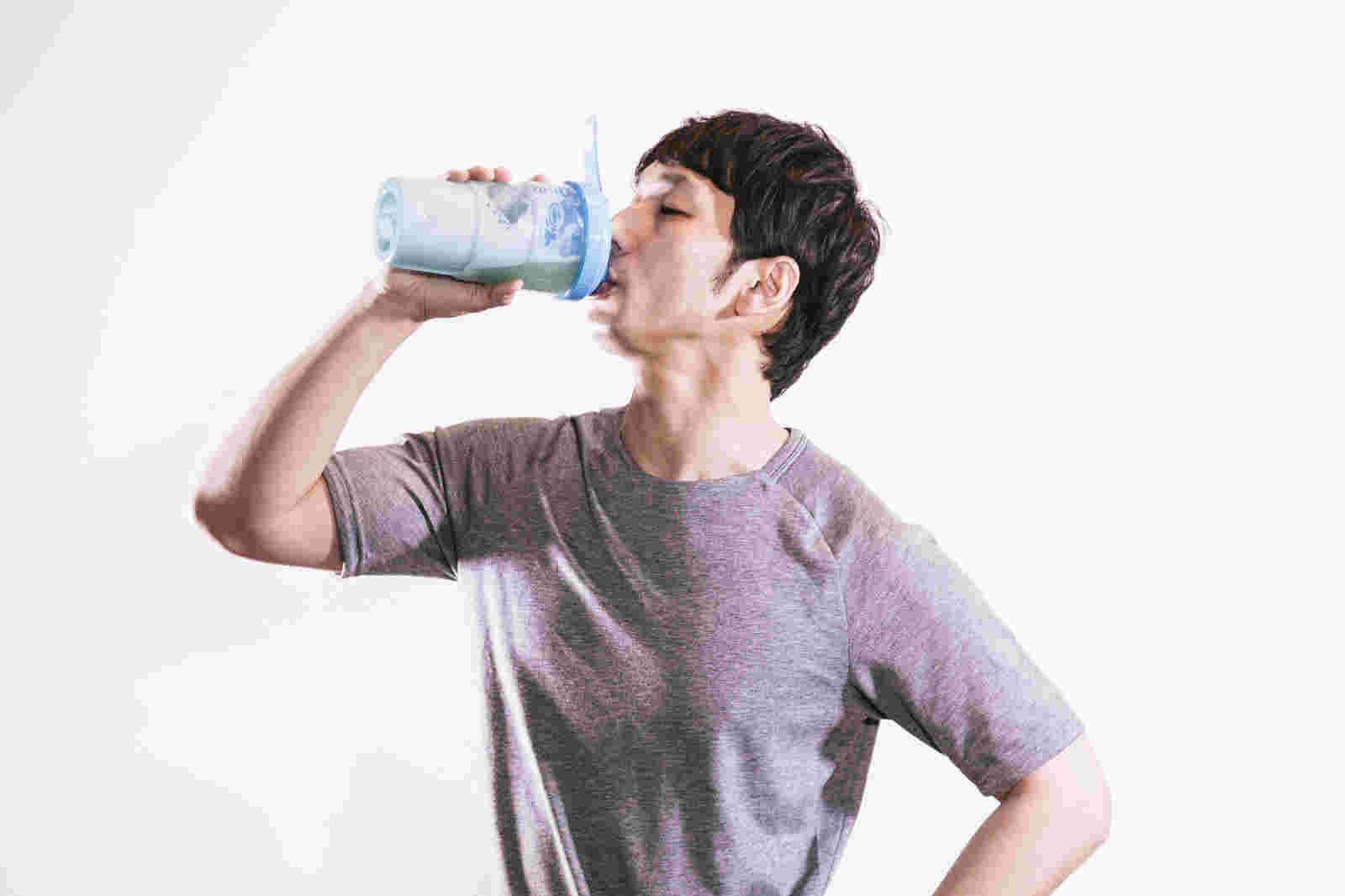 健康ドリンクを腰に手を当てて飲む男性