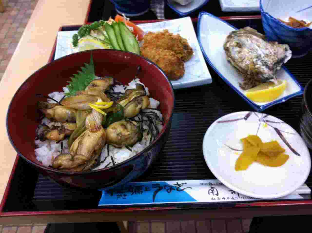 ご飯の上に沢山の大きな牡蠣が乗った牡蠣丼とカキフライのセットの画像