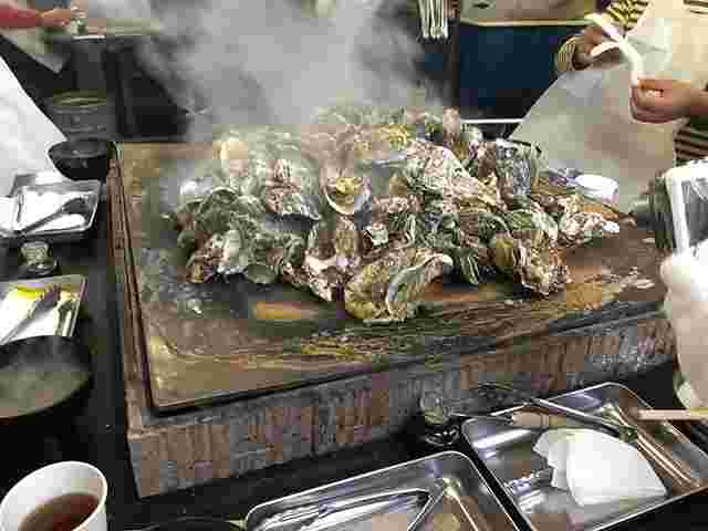 沢山の牡蠣が鉄板上で焼かれている美味しそうな画像