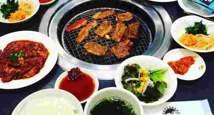テーブルに色んな食べ物と網には肉が焼かれている
