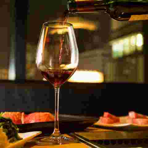 夜景が見える席に置かれたお肉とワイン
