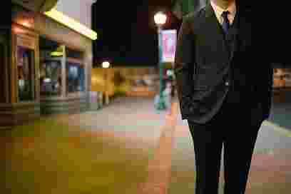 夜の街を歩くスーツの男性