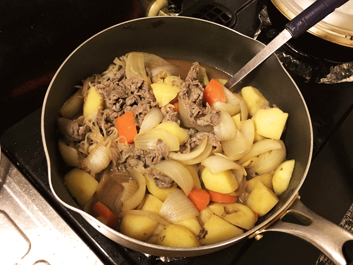 深いフライパンで肉じゃがを作っている