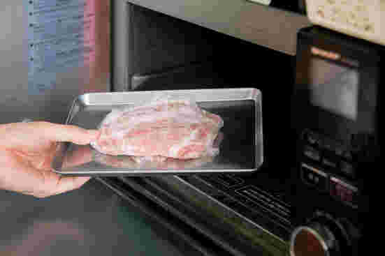 電子レンジに肉を入れようとしている
