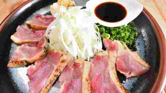 鶏肉のタタキの真ん中に長ネギのスライスが盛り付けてある美味しそうな画像
