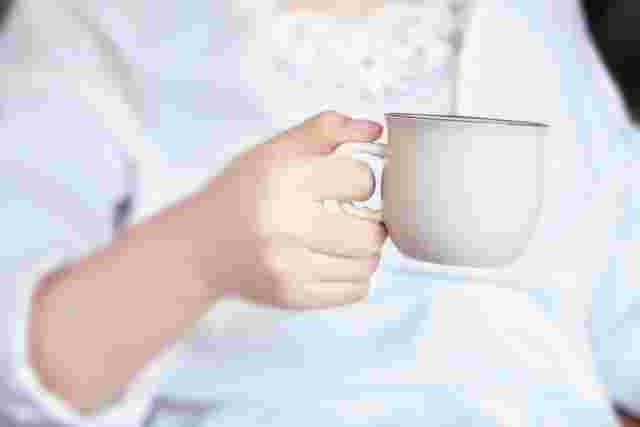 温かい飲み物が入ったカップを手にする女性