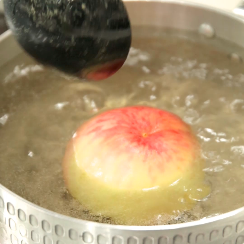 鍋のなかに桃を入れる