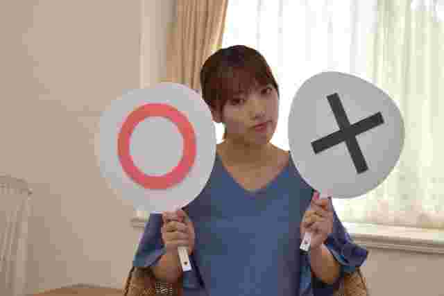 〇と×の札をもっている女性