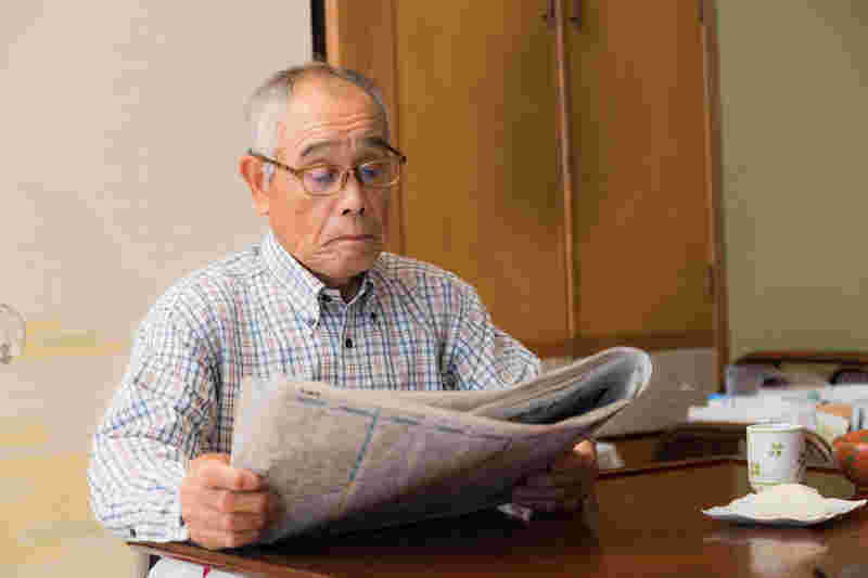 新聞を読む高齢者