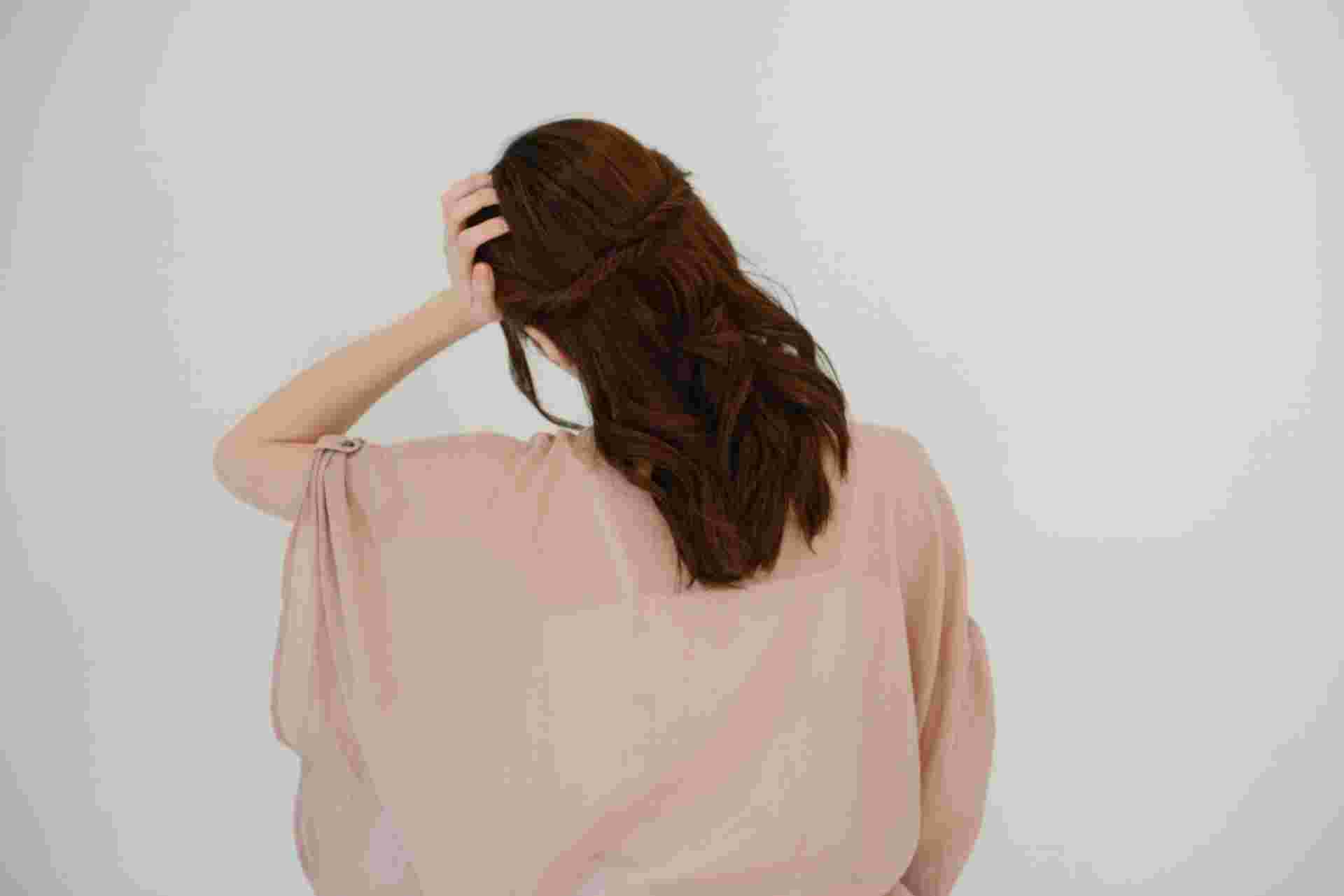 頭痛で頭に手を添える女性