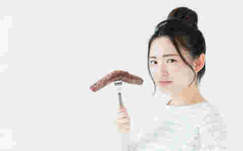食べ物を持ってダイエットをしようかどうか迷っている女性