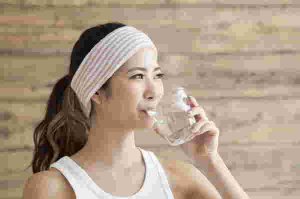 コップの水でこうじ酵素を飲んでいる女性の写真