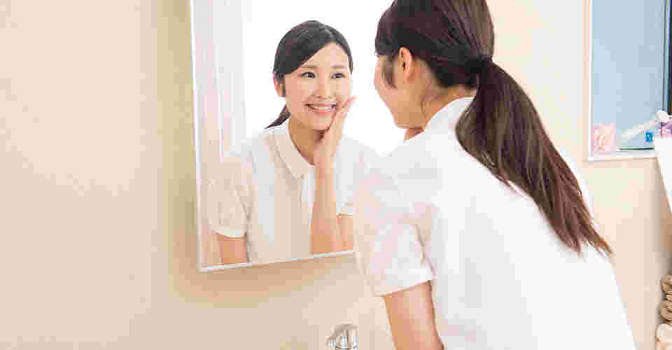 鏡を見てむくみが取れたことを確認している女性