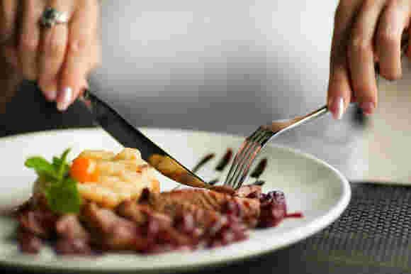 皿の上の料理を食べようとする女性の手