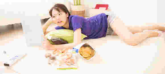 横になってポテチを食べている女性