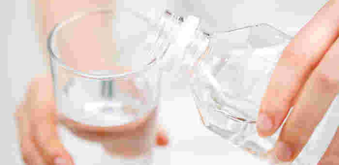 ペットボトルからコップに水を注いでいる様子