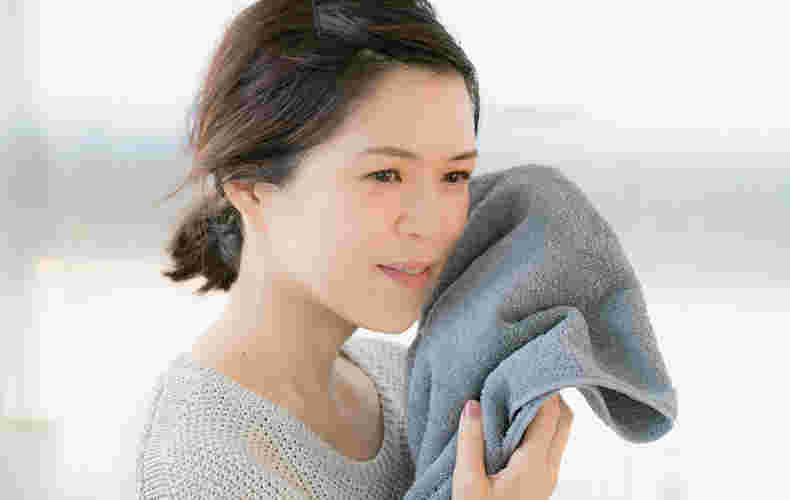 タオルを顔にあてて遠くを見つめる女性