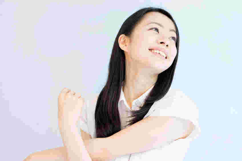 腕のストレッチをしながら遠くを見る女性