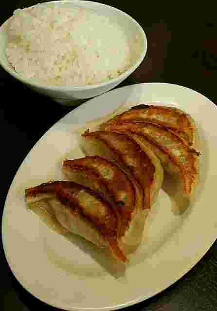 白ご飯と餃子が食卓に乗っている画像